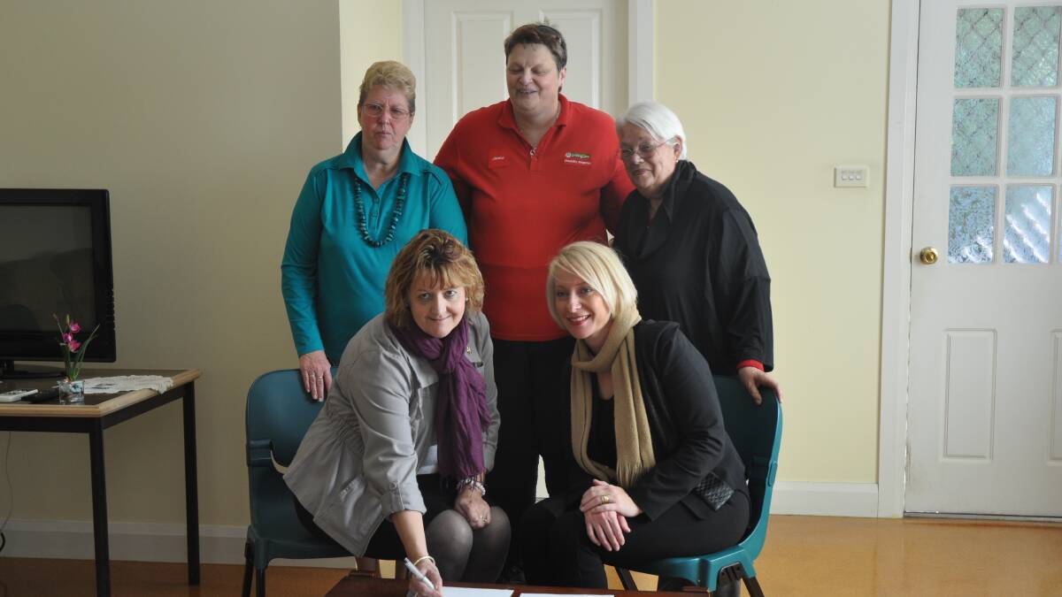 WINNING PARTNERSHIP: UnitingCare Disability Singleton committee members Maureen Timmins, Julia Crebert and team leader Janice Lawrence watch on as their former chairperson Megan Lobb signs an agreement with UnitingCare Disability acting director Fiona Coluccio.