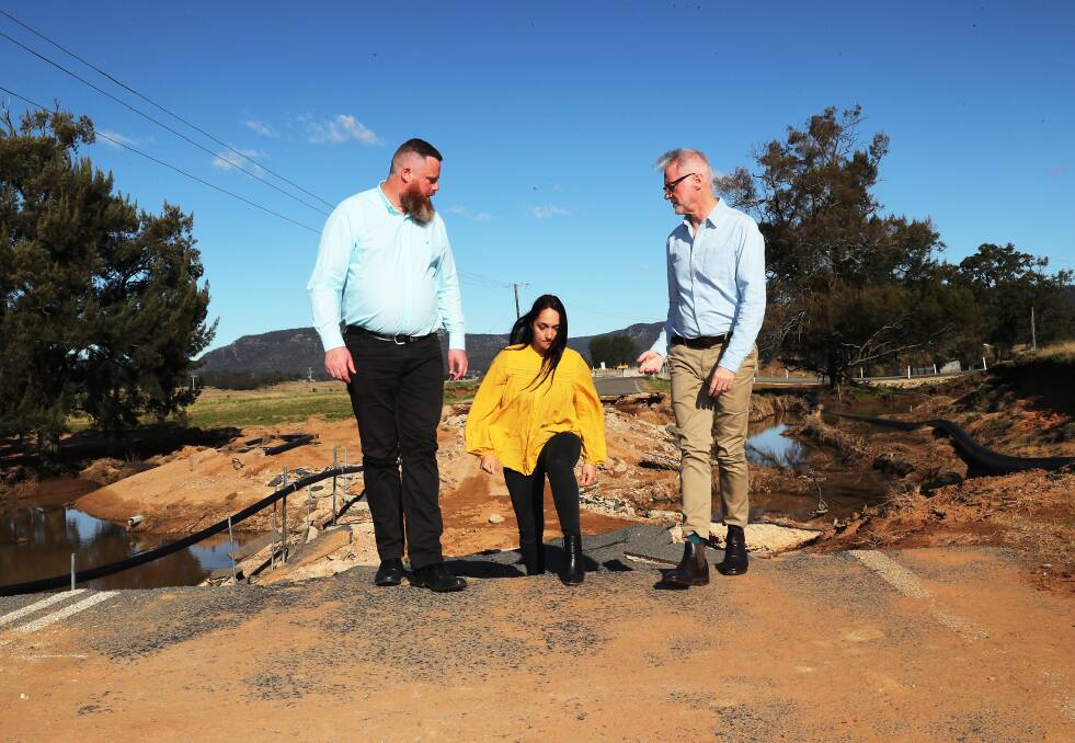 Resillience: Dan Repacholi, Angela Andonopoulos and Senator Tony Sheldon at the damaged section of Broke Road. Picture: Peter Lorimer