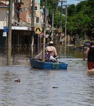 People waded through water and move through the streets of Lismore in NSW on boats during the 2022 flood events. Picture by Cathy Adams
