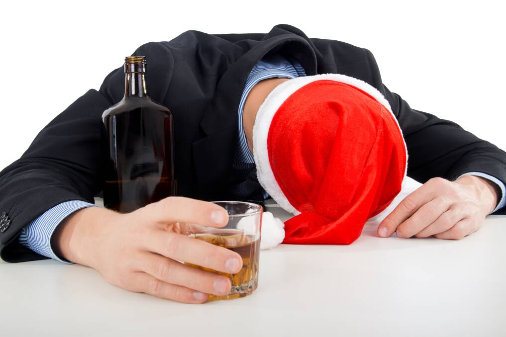 Man drinking in Santa hat at Christmas party. File Picture