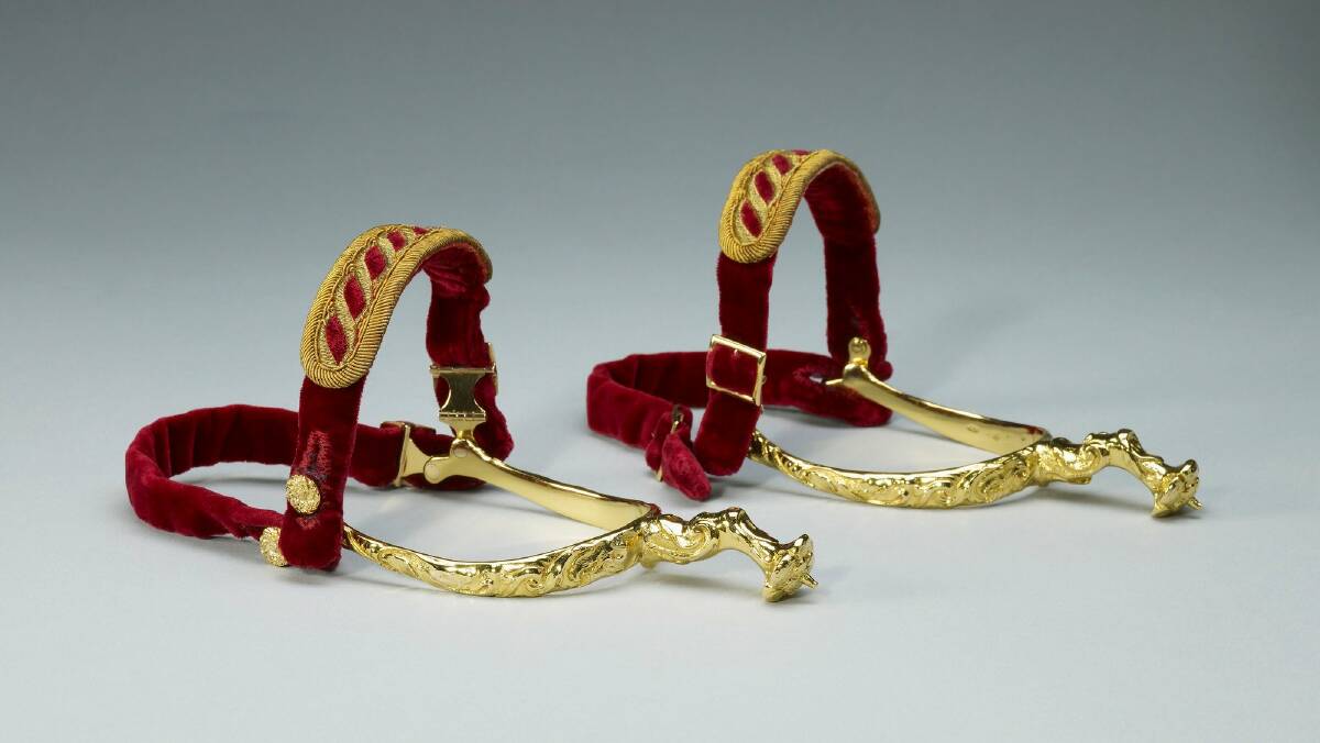 The gold spurs. Each features a Tudor rose and a velvet-covered strap with gold embroidery. Picture by Royal Collection Trust.