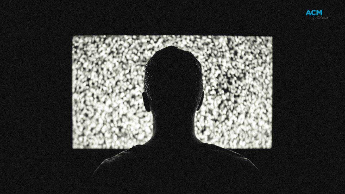 The silhouette of a person sitting in front of the TV. Picture via Canva