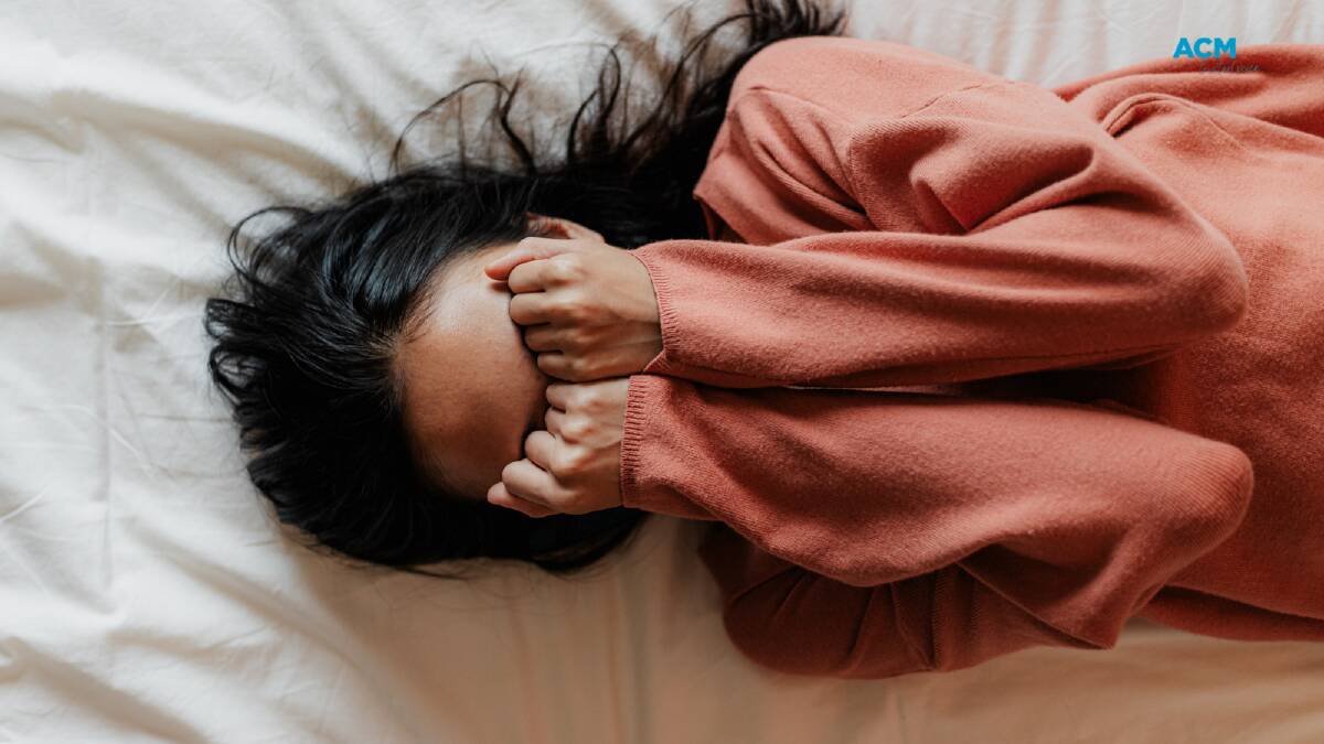 A woman lying on a bed covering her eyes, overcome with stress. File picture.