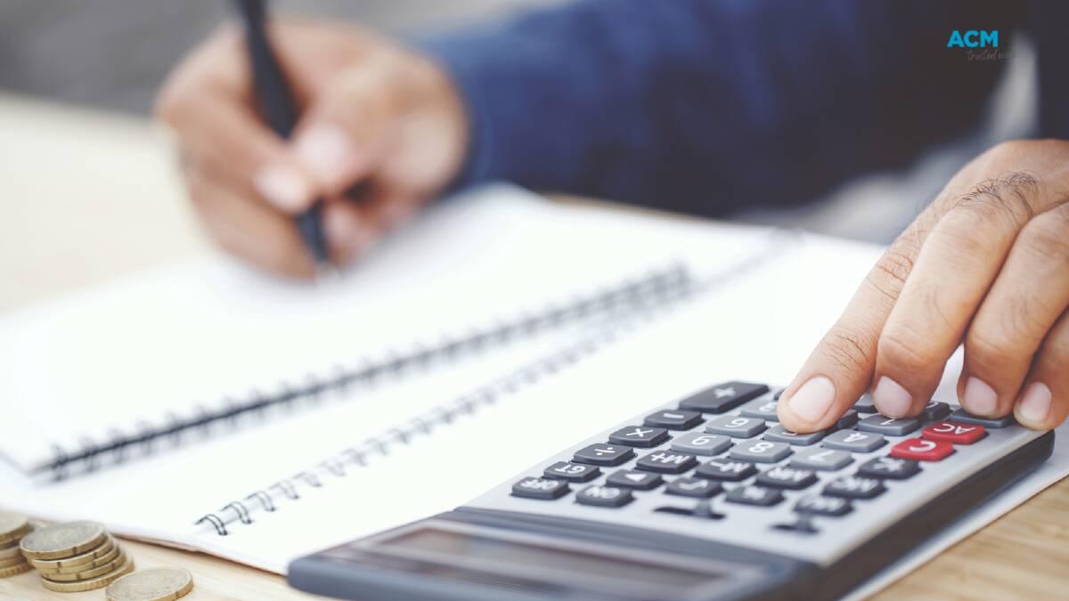 Working at a desk with a calculator and notebooks. Picture via Canva