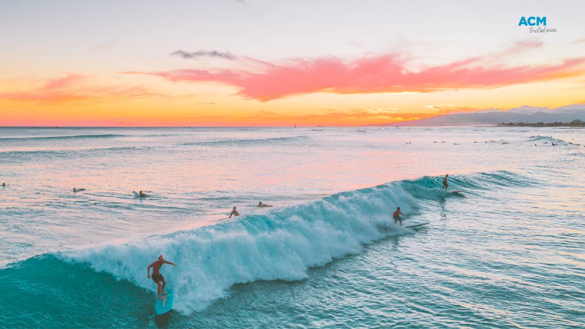 Surfers ride breaking waves at sunrise. File picture.
