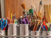 Arts supplies, including coloured pencils and paintbrushes, organised in tins. File picture.