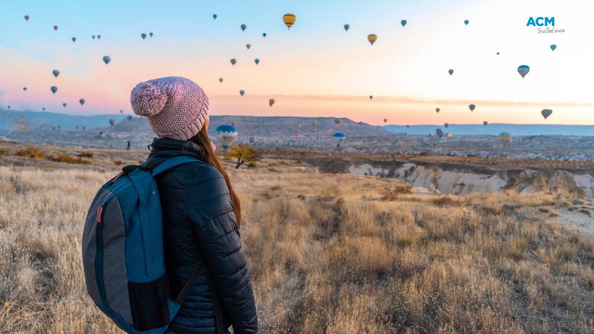 A young tourist watches hot air balloons over Cappadocia. Picture via Canva