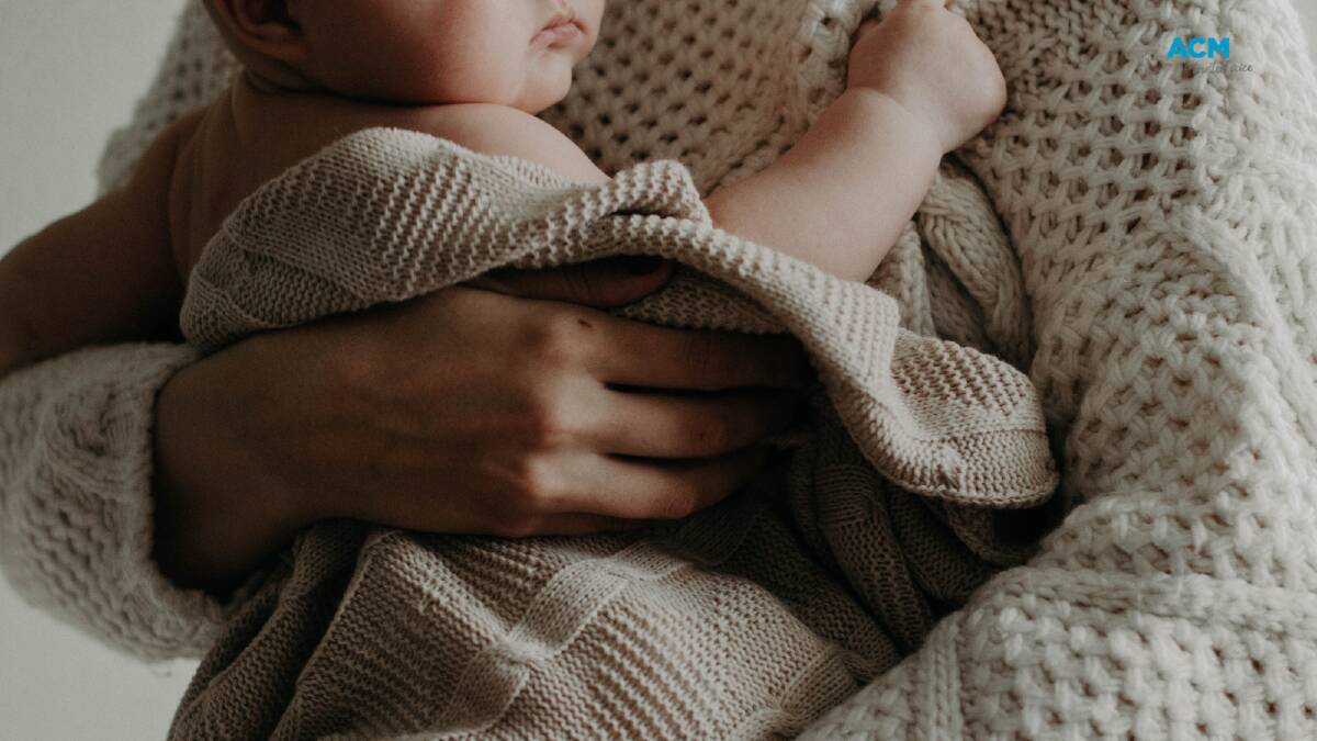 A baby wrapped in a knitted blanket. Picture by Polina Tanklevitch via Canva