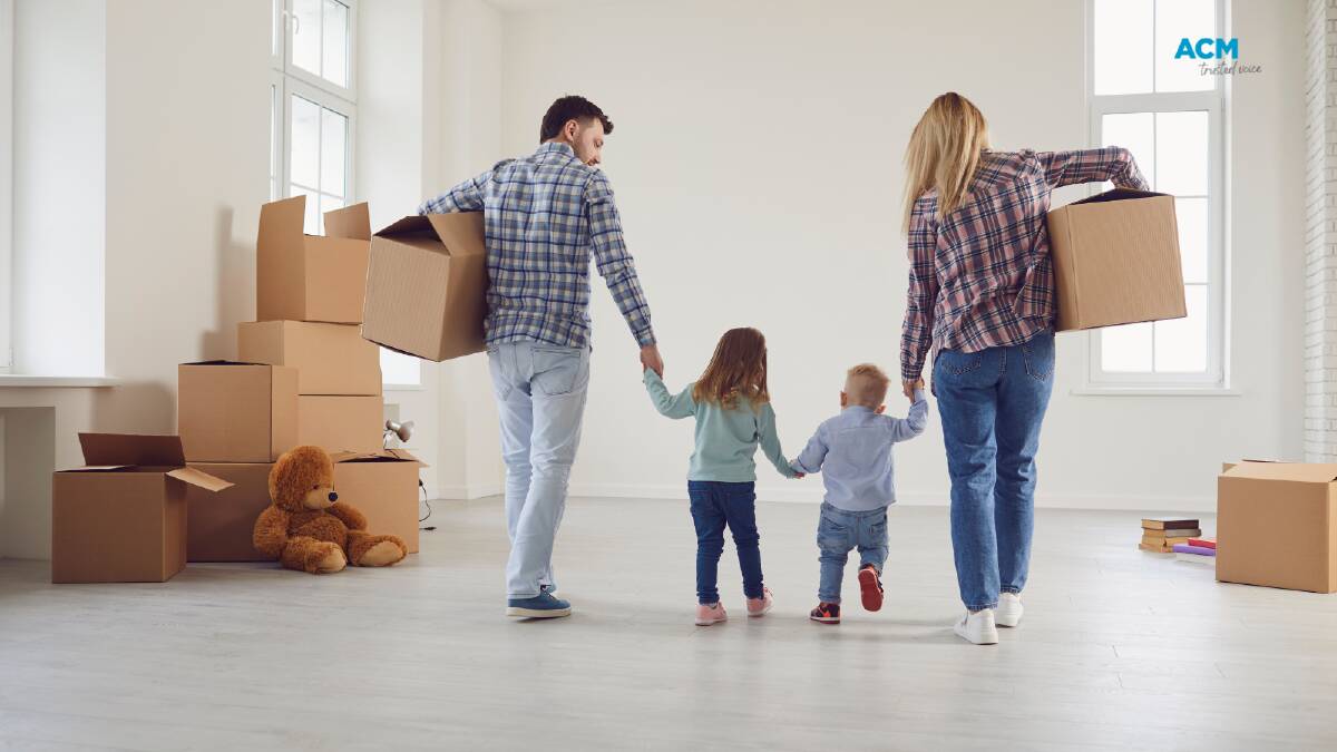 Two adults and their children carry boxes into a new home. File Picture.