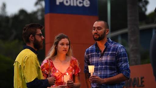 Members of the local community take part in a vigil at Calamvale police station, Calamvale, south of Brisbane, Queensland, Tuesday, December 13, 2022. Constables Matthew Arnold, 26, and Rachel McCrow, 29, died in an ambush and siege at a remote Queensland property. (AAP Image/Jono Searle)