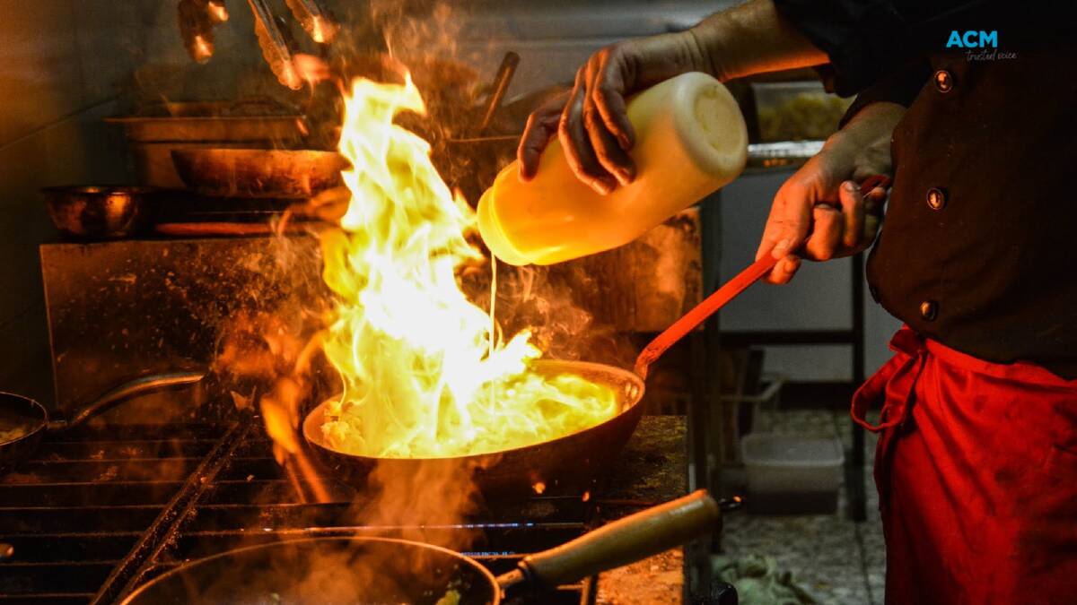 Chef pours liquid into pan, managing a small flambé. File picture.
