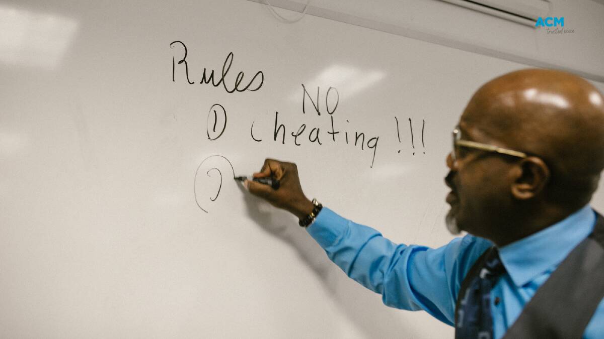 A lecturer writes class rules on the whiteboard. File picture.
