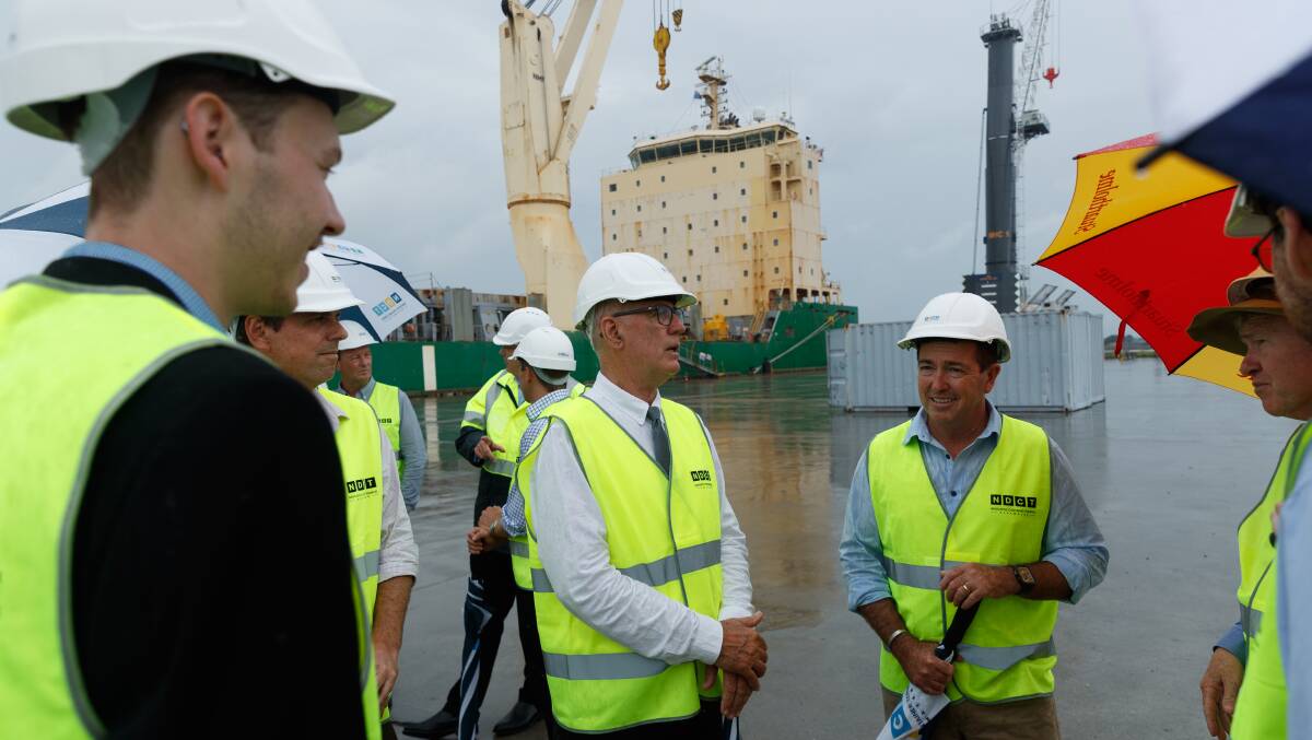 Deputy Premier Paul Toole, right, with umbrella, at the Port of Newcastle yesterday. Mr Poole told media of a meeting with coal companies and the NSW Minerals Council that was held later in the day. He is pictured here with Lake Macquarie MP Greg Piper to hils left, and Upper Hunter Nationals MP Dave Layzell, beside Mr Piper. Picture by Max Mason-Hubers