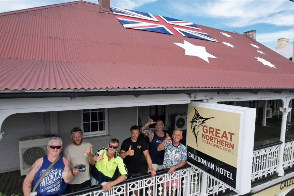 The crew who installed the Union Jack and Southern Cross on The Cali roof toast their handiwork. Picture by the Caledonian Hotel
