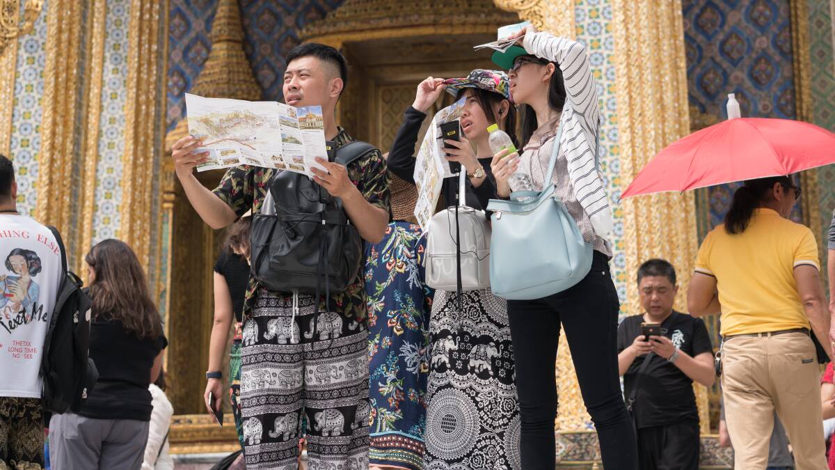 Chinese travellers refer to a tourist brochure while visiting Wat Phra Kaew at Grand Palace, Bangkok. Picture Shutterstock