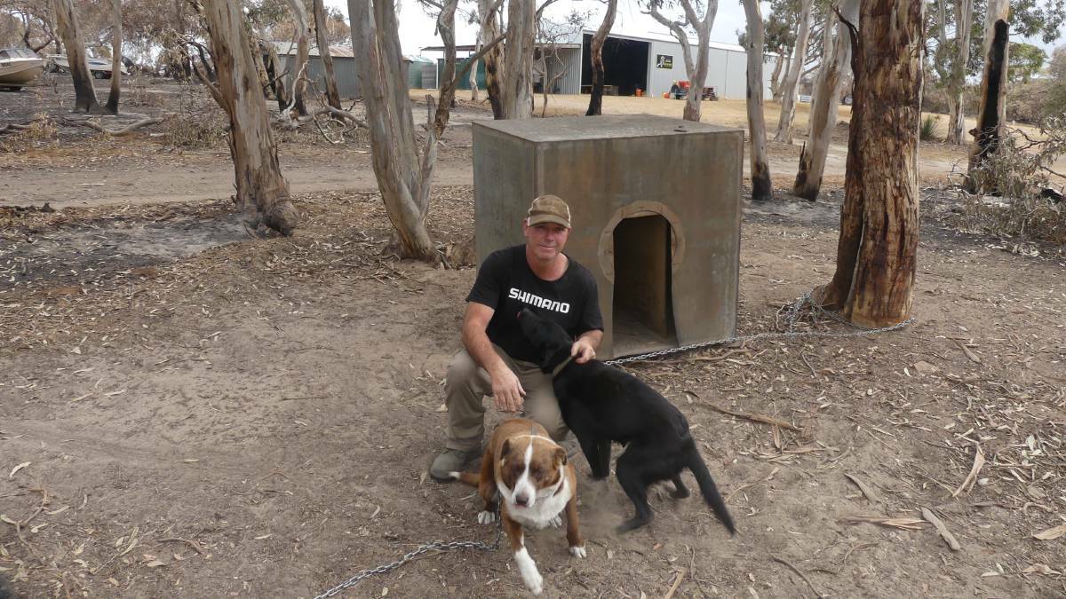SURVIVORS: Kangaroo Island garlic grower Shane Leahy with his dogs Socks and Lucy that along with their pups, including Dusty, survived the bushfire, along with his garlic processing shed in the background.