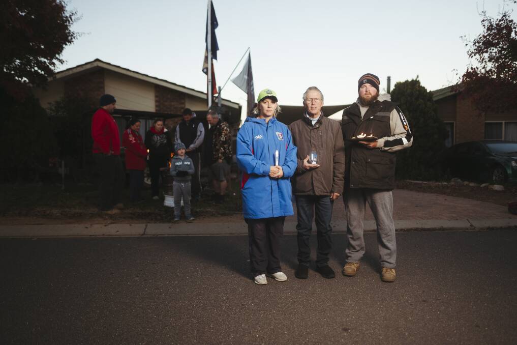 Carrie Mitchell, Greg Jackson, Shaun Mitchell with neighbours outside their homes for the Anzac Day Light up the Dawn driveway service. Picture: Dion Georgopoulos 