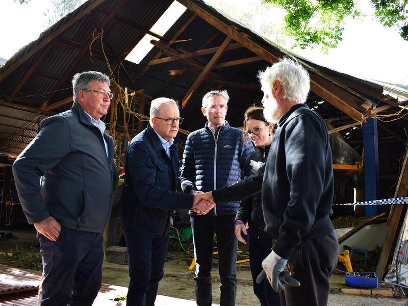 Prime Minister Anthony Albanese, second left, meets a local in the flood-hit NSW town of Eugowra. (Murray McCloskey/AAP PHOTOS)