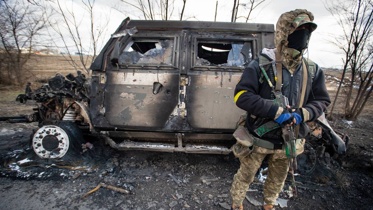 A Ukrainian soldier stands beside a burnt-out Russian Tigr fighting vehicle destroyed by his unit east of the strategic port city of Mykolaiv earlier this month. Picture: Getty Images